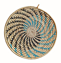 Woven trivet placemat with black and blue spiral pattern on a white background