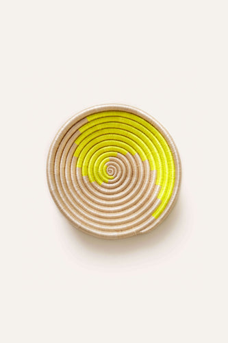Round woven basket with neon yellow spiral pattern on a white background