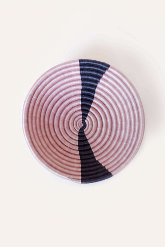 Round woven basket with concentric circle pattern on a white background