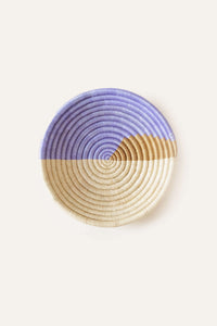 Round woven basket with purple and beige pattern on a white background