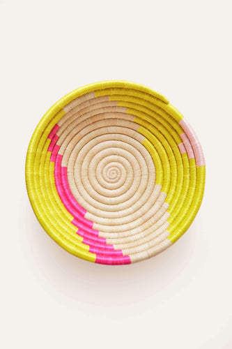 Woven basket with neon pink and yellow spiral pattern on a white background