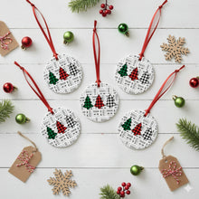 Round Christmas ornaments with red ribbons on a white wooden surface with festive decorations.