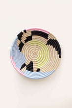 Woven african basket with pale pink, green and blue colors in an abstract circle pattern on a light background