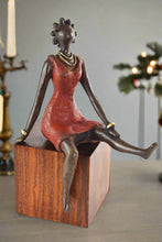 Bronze sculpture of a woman in a red dress on a wooden base