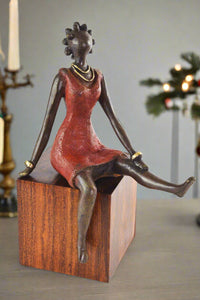 Bronze sculpture of a woman in a red dress on a wooden base