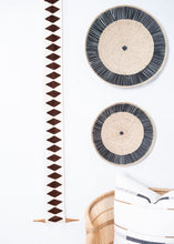 Two circular woven rugs with black and beige patterns on a white background.