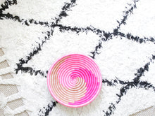 Pink and beige basket on a white and black patterned area rug