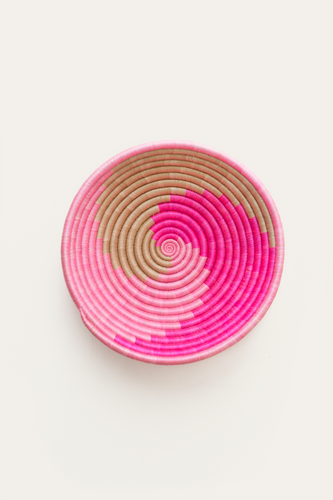 Pink and beige woven circular basket on a white background
