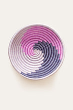 Decorative african basket with pink, purple, and white spiral pattern on a light background