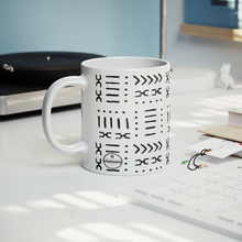 11 ounce white coffee mug with black abstract African pattern on a table next to a record player