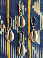 Silver shell-shaped keychains on a patterned fabric background