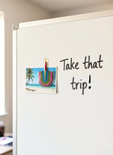 Whiteboard with a motivational quote and a beach photo, held by an african fridge magnet in an office.