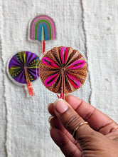 Colorful fridge magnets held by a hand on a textured fabric background