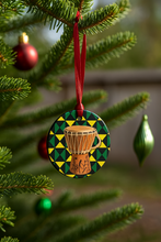 Decorative ornament with a drum design hanging on a Christmas tree.