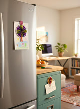 Kitchen with a magnet on the refrigerator and a metal file cabinet with a magnet on it in an office area in the background