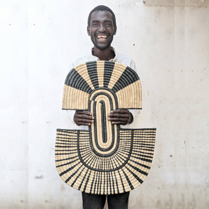 Man holding a large woven basket with geometric pattern against a light background