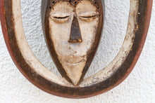 Wooden mask with a face design on a textured white background