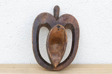 Wooden apple-shaped wall mask on a white background