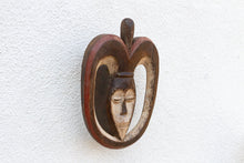 Decorative mask with a face design on a textured white background