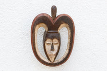 Decorative wall hanging with a heart-shaped design and face on a textured white background