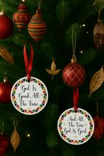 Decorative Christmas ornaments with religious phrases on a tree.