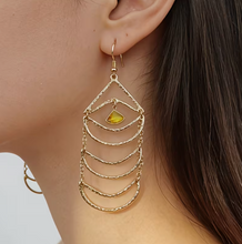 Gold chain earring with a yellow gemstone worn by a person