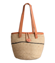 Woven basket bag with brown leather handle and trim on a white background