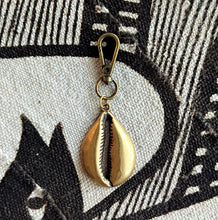 Brass metal cowrie shell keychain on a textured fabric background