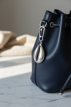 Black leather handbag with a silver pendant on a marble surface