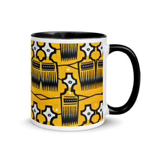 A ceramic coffee mug with a black handle and a yellow and black geometric tribal pattern