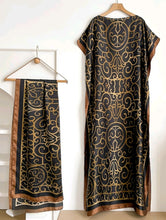 Black and gold patterned kaftan dress on a hanger against a white background