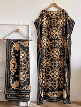 Black and gold patterned kaftan dress with scarf on hangers against a white background