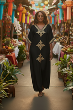 Woman in a black dress with gold patterns walking through a vibrant market with colorful lanterns and stalls.