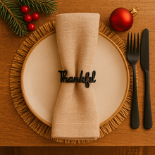 Thankful napkin holder on a plate with Christmas decorations on a wooden table