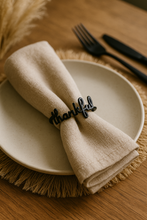 Napkin with 'thankful' clip on a plate with cutlery on a wooden table