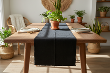 A solid black mud cloth fabric table runner or scarf laid out flat.