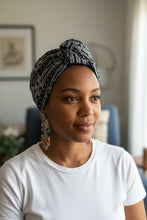 Woman wearing a patterned headscarf and white shirt indoors