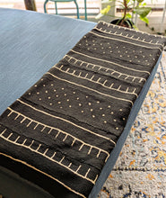 Black and white mud cloth fabric throw on a chaise lounge chair.