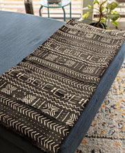 Black and white mud cloth fabric on a blue chaise lounge with a blurred indoor background