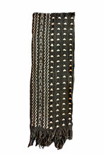 A black woven textile scarf with geometric patterns in cream and white, featuring fringed ends, shown against a plain white background.