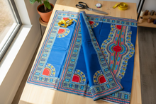 Blue fabric with red and green patterns on a wooden table.