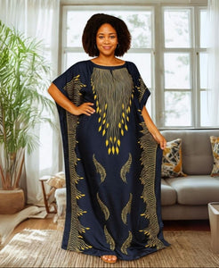 Woman wearing a long, dark blue kaftan dress with gold patterns in a living room.