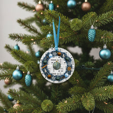 Decorative ornament with blue ribbon hanging on a Christmas tree with other ornaments.