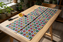 Colorful patterned african fabric on a wooden table with scissors in a home setting.