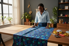 Woman working with fabric on a table in a home setting