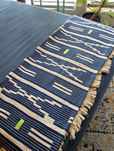 Blue and beige patterned throw blanket with green accents on a surface.