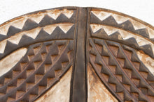 Close-up of a decorative wood mask with geometric patterns on a white background
