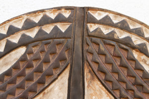 Close-up of a decorative wood mask with geometric patterns on a white background