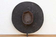 Decorative wall piece with a round, dark finish on a white background