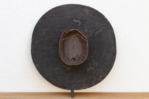 Decorative wall piece with a round, dark finish on a white background